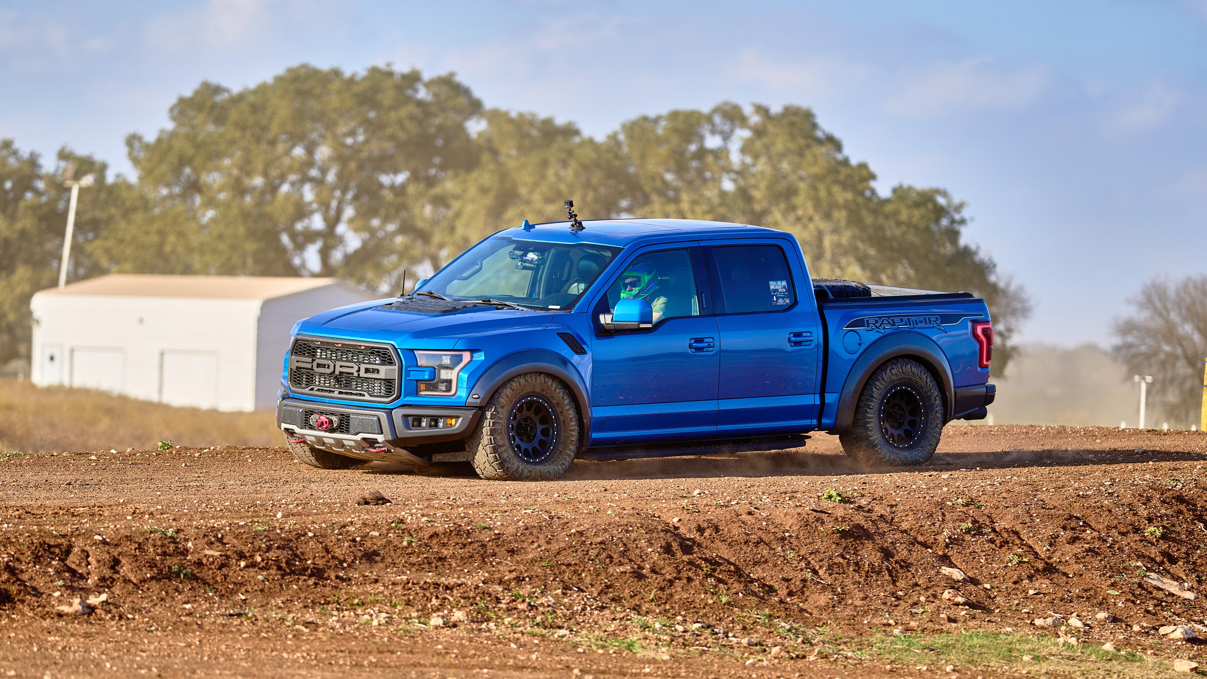 Ford Raptor launching off dirt mound — front view