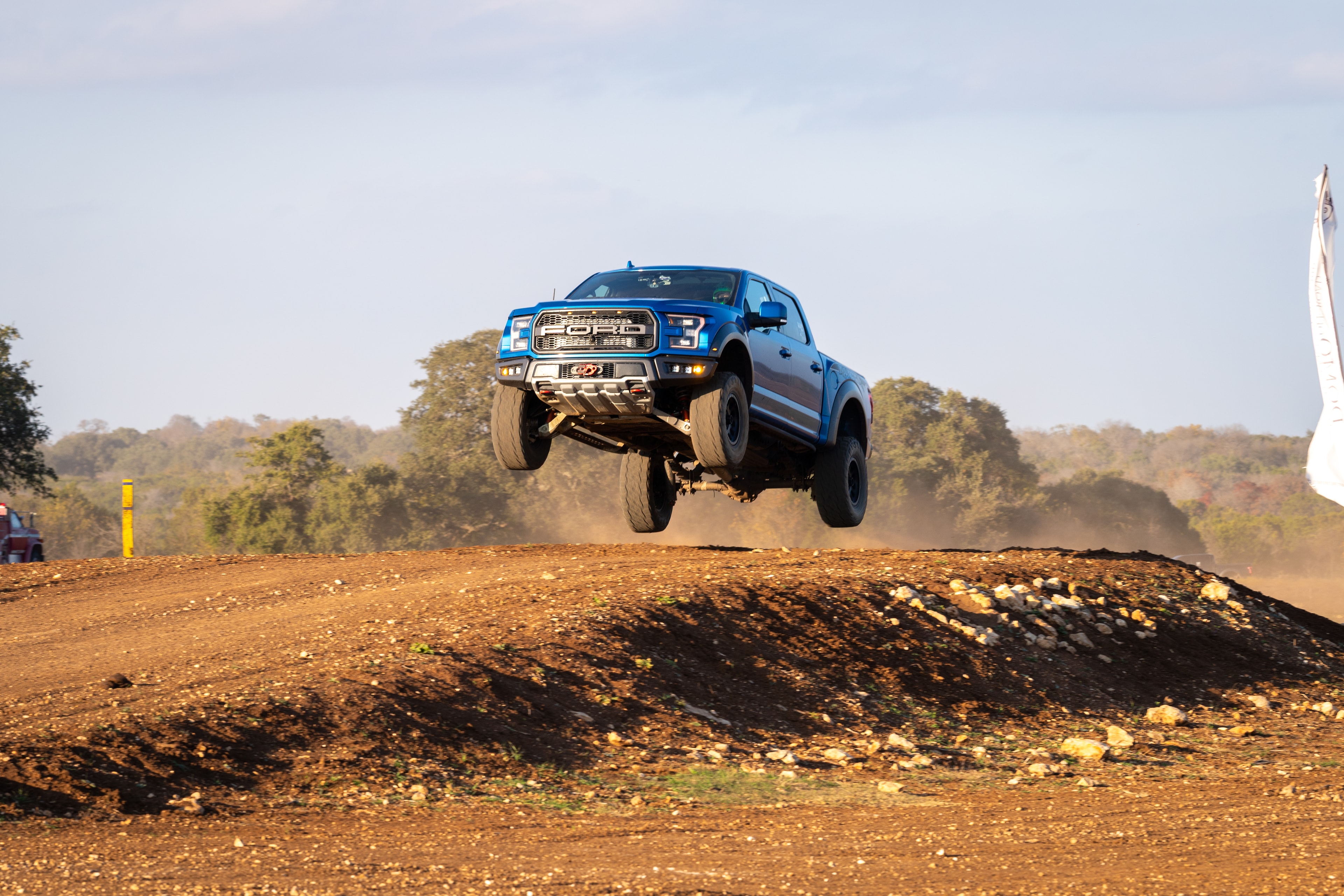 Ford Raptor launching off dirt mound — front angle